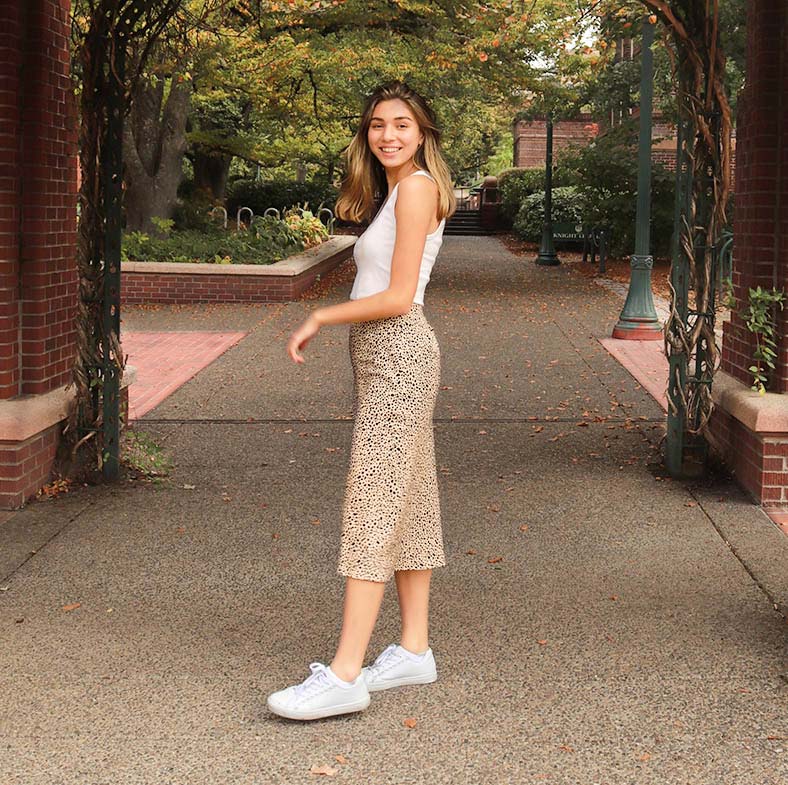 Abby standing under an outdoor arch and smiling at the camera