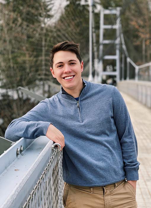 Clay smiling at the camera while leaning on a bridge railing