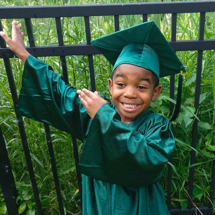 Dayna’s son posing in a green elementary graduation outfit